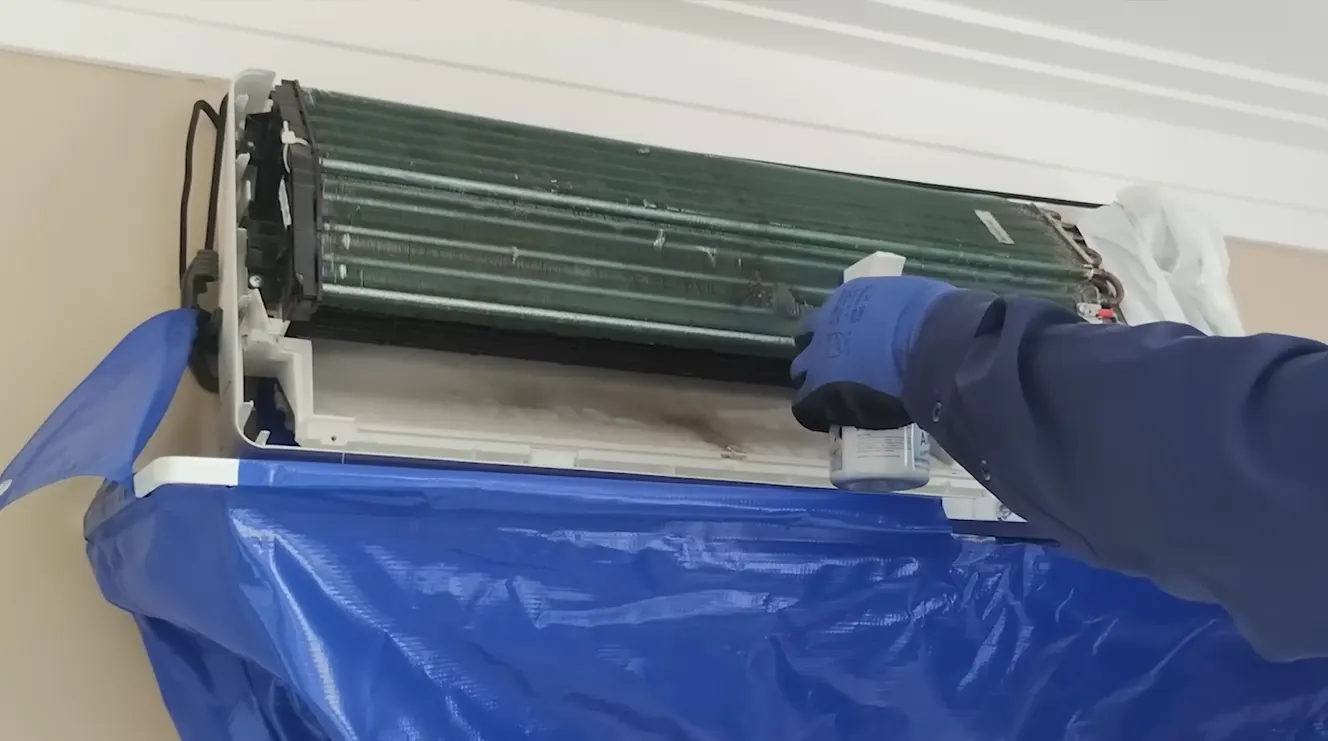 Técnico lavando unidade externa de ar-condicionado durante higienização